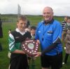 St Brendan's Captain Niall McCormick is presented with the U12 Hurling Shield by North Antrim Official John Mc Henry